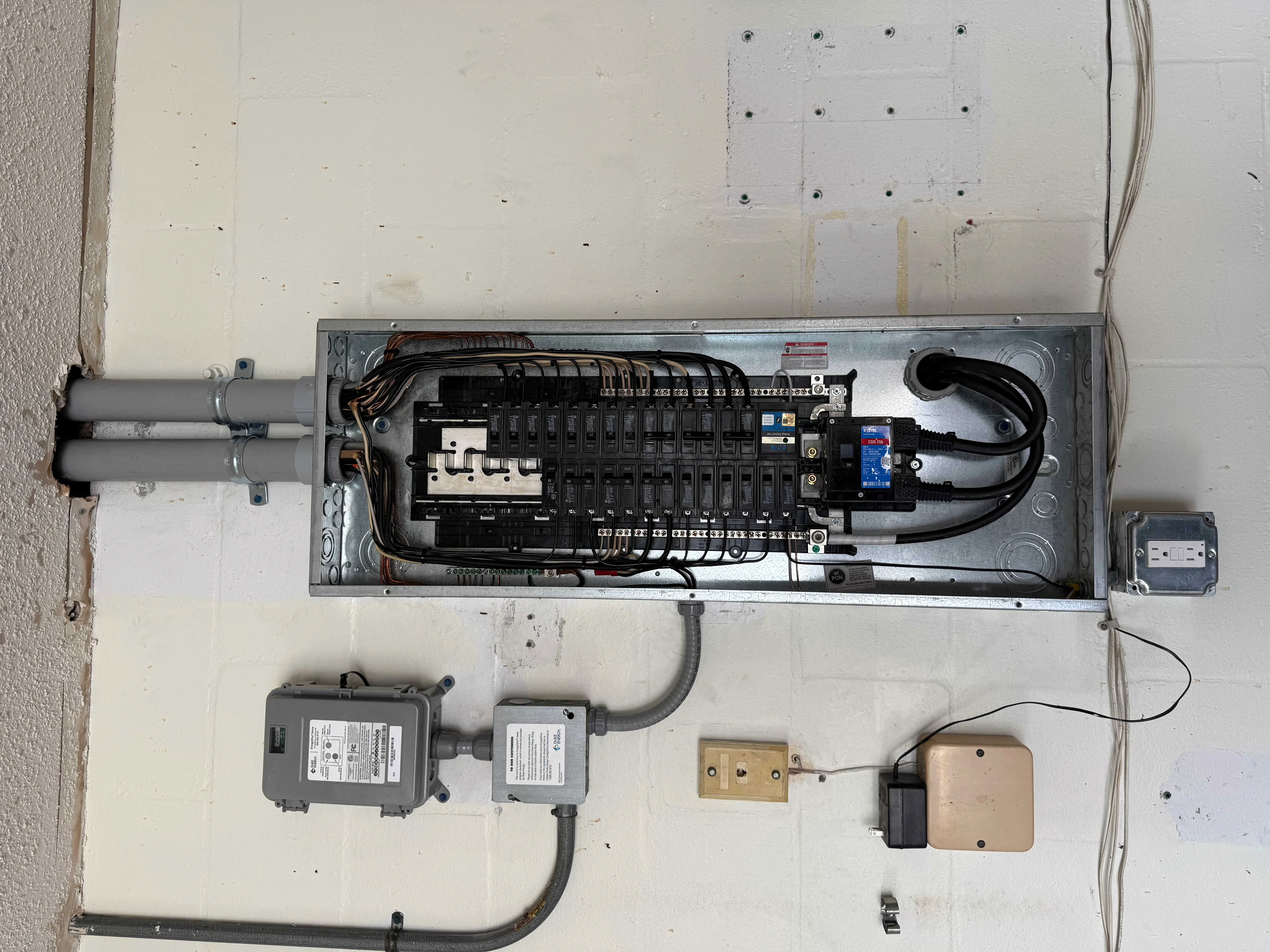 Electrical panel with breakers, surge protection, and conduit wiring installation on drywall