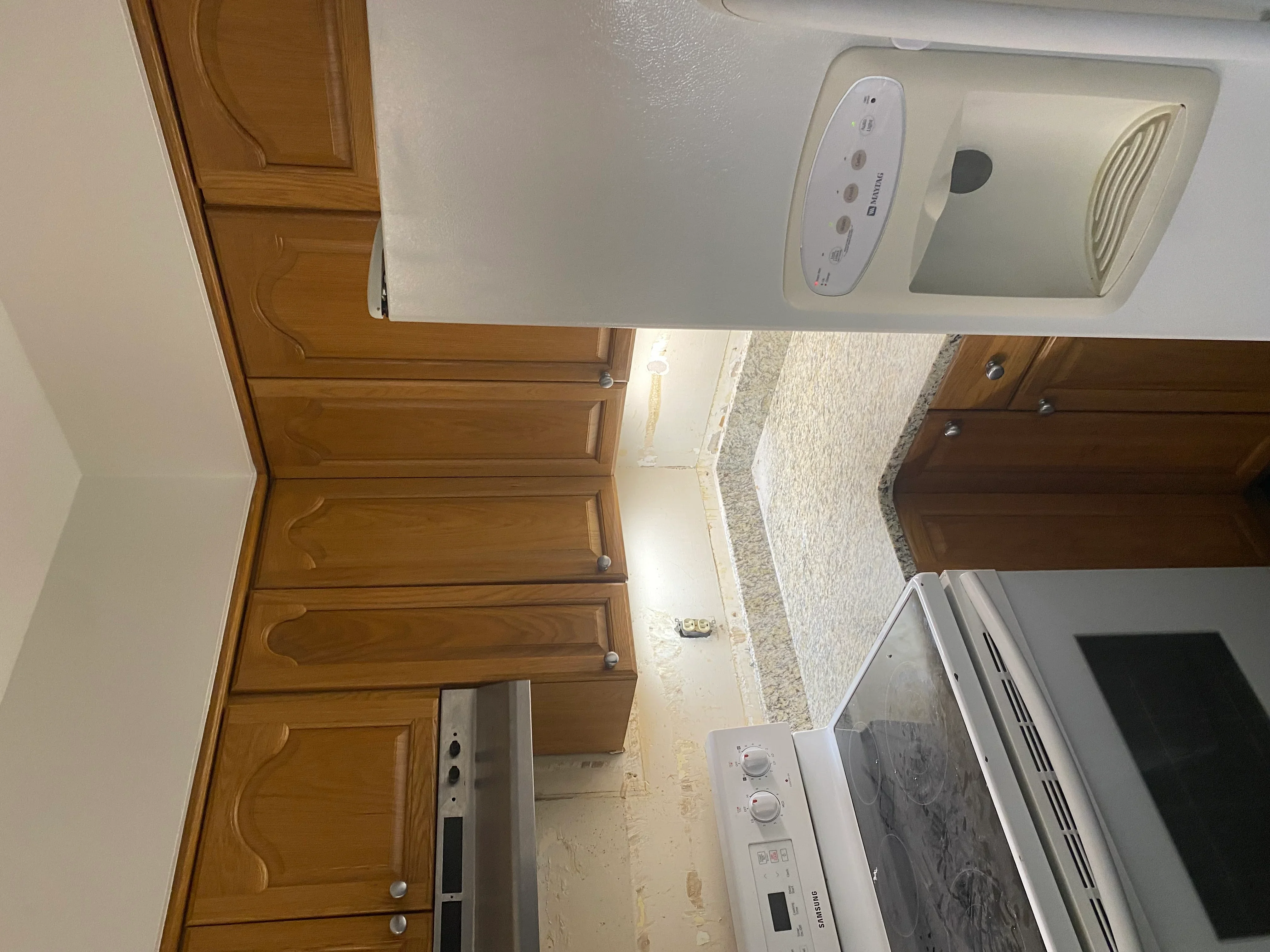 Ceiling-mounted exhaust fan with white control panel and light fixture installed above kitchen cabinetry