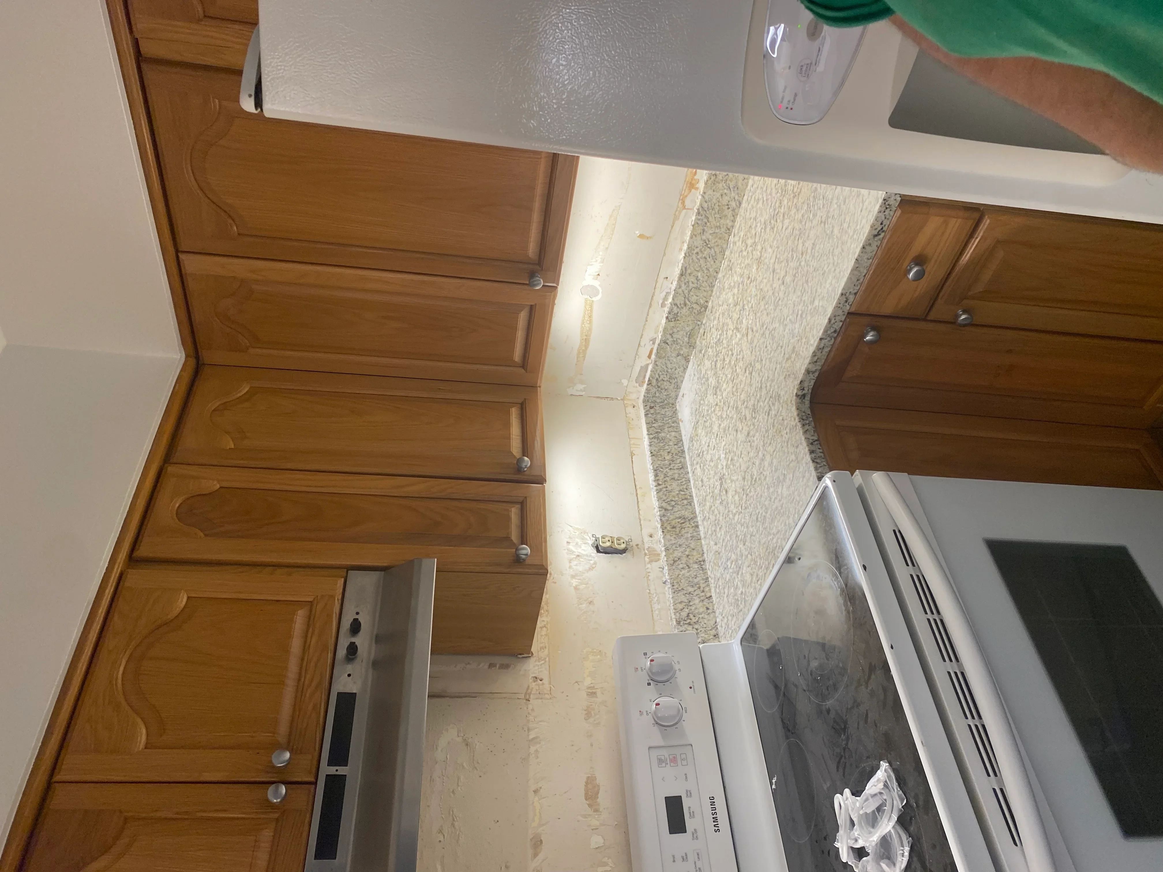 Kitchen electrical outlets and wiring installed along wooden cabinetry and granite countertop